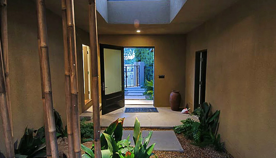 Modelo de puerta principal tropical de tamaño medio con paredes beige, suelo de cemento, puerta simple, puerta de madera oscura y suelo gris