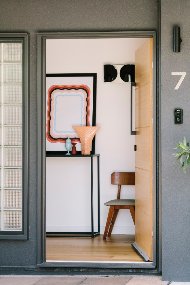Immagine di una piccola porta d'ingresso minimalista con pareti bianche, parquet chiaro e una porta in legno bruno