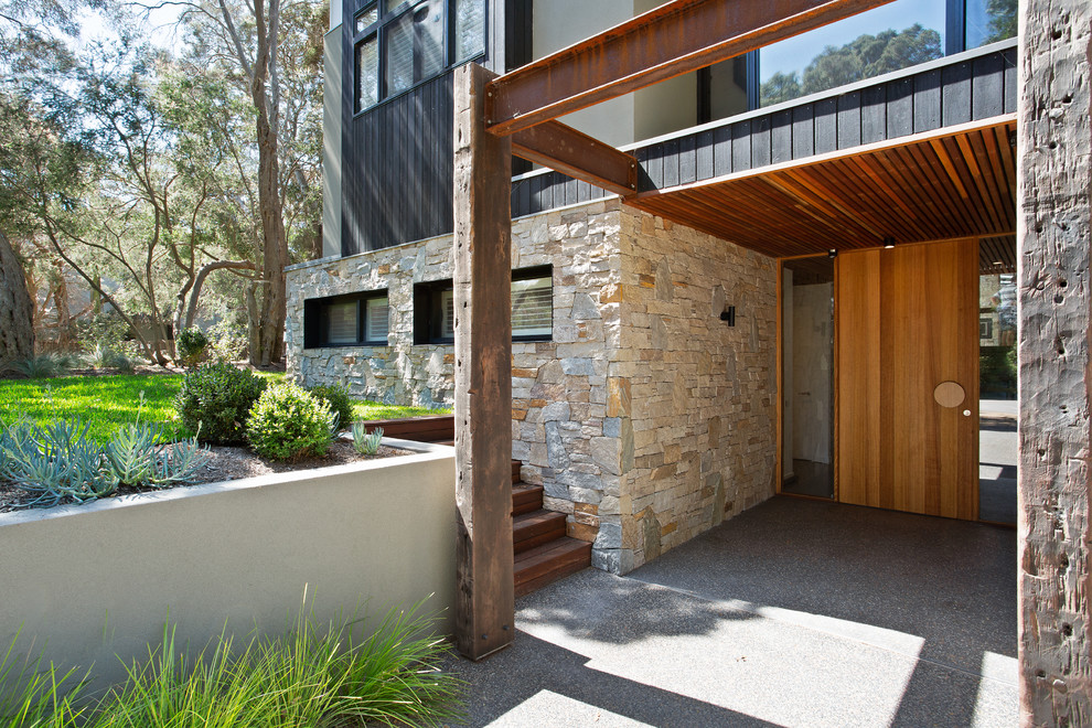 Bild på en mellanstor funkis ingång och ytterdörr, med bruna väggar, betonggolv, en enkeldörr, ljus trädörr och brunt golv