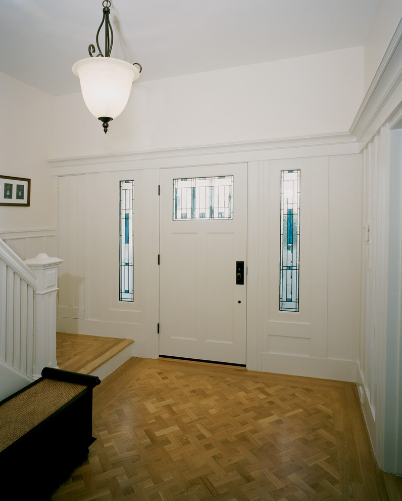 Idées déco pour une très grande porte d'entrée classique avec un mur blanc, un sol en bois brun, une porte simple et une porte blanche.