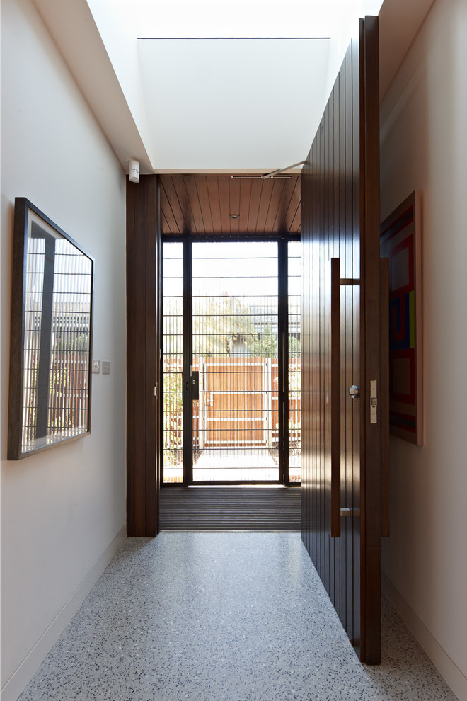 Exemple d'une grande entrée tendance avec un couloir, un mur blanc, sol en béton ciré, une porte simple et une porte en bois foncé.