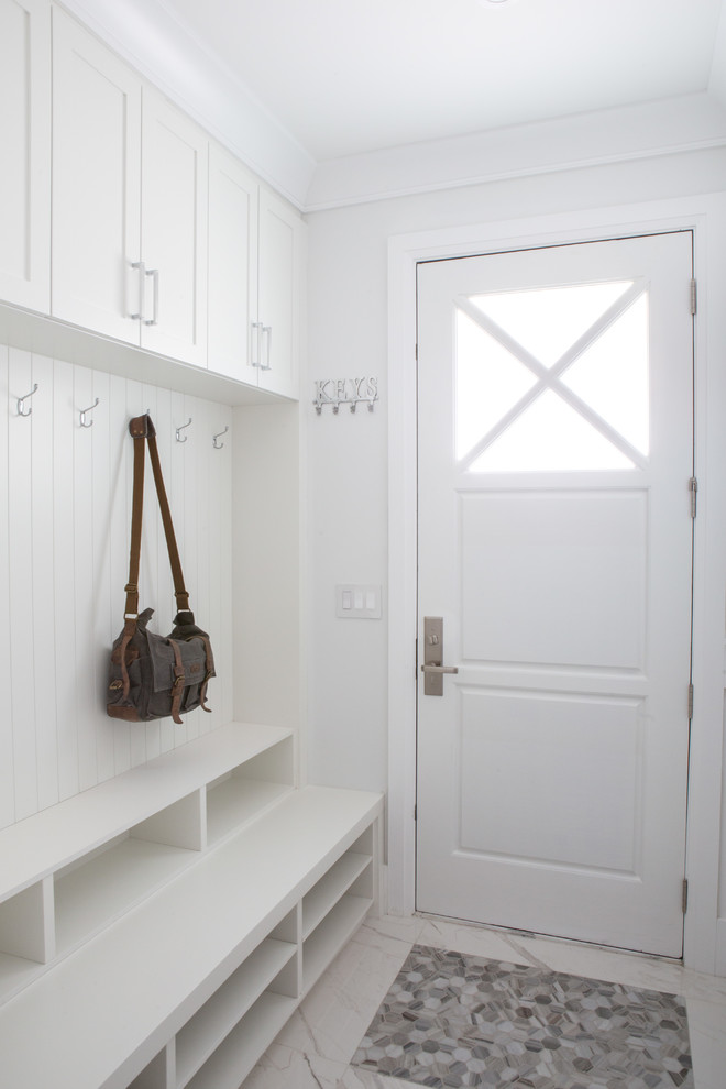Cette photo montre une entrée chic de taille moyenne avec un vestiaire, un mur blanc, un sol en marbre, une porte simple, une porte blanche et un sol blanc.