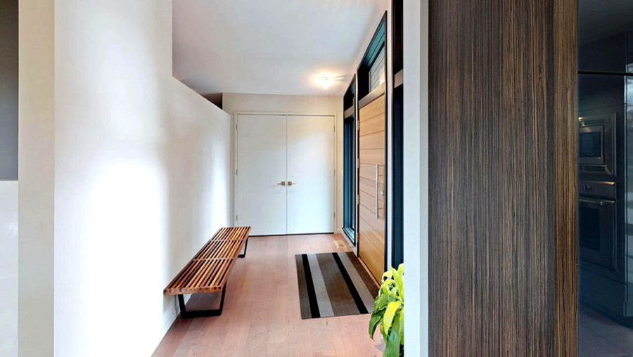 Diseño de distribuidor moderno pequeño con paredes blancas, suelo de madera clara, puerta simple y puerta de madera clara