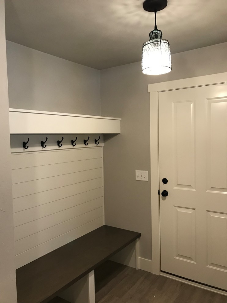 Photo of a medium sized farmhouse boot room in Other with vinyl flooring, brown floors, grey walls, a single front door and a white front door.
