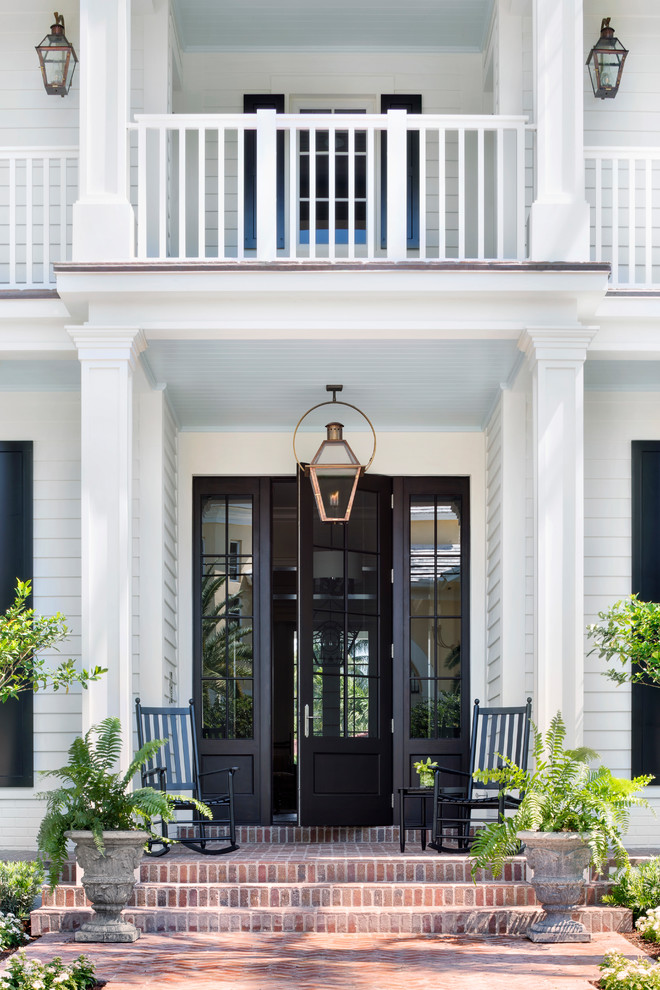 Design ideas for a traditional front door in Miami with white walls, a single front door, a black front door, red floors and feature lighting.