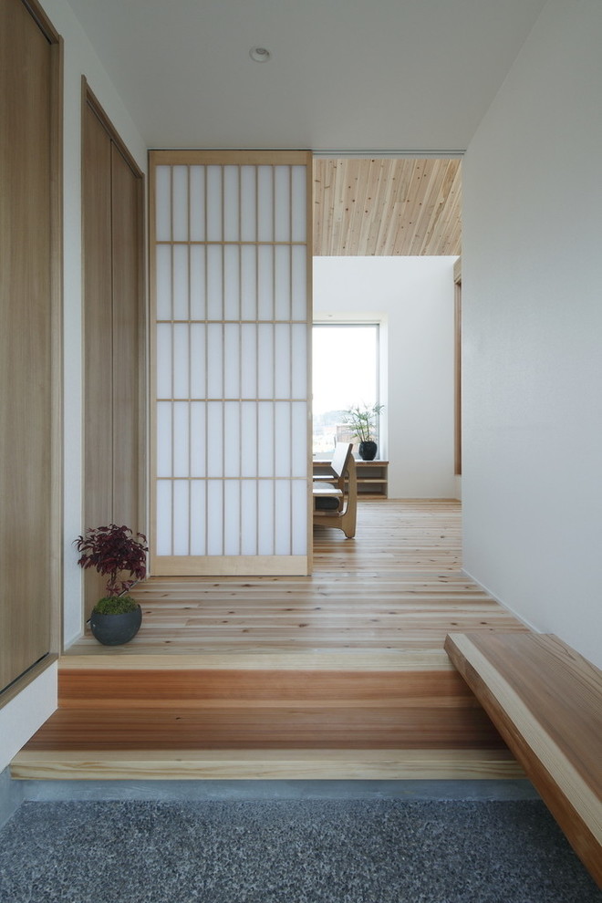 Aménagement d'une petite entrée avec un couloir, un mur blanc, parquet clair, une porte simple, une porte en bois clair et un sol beige.