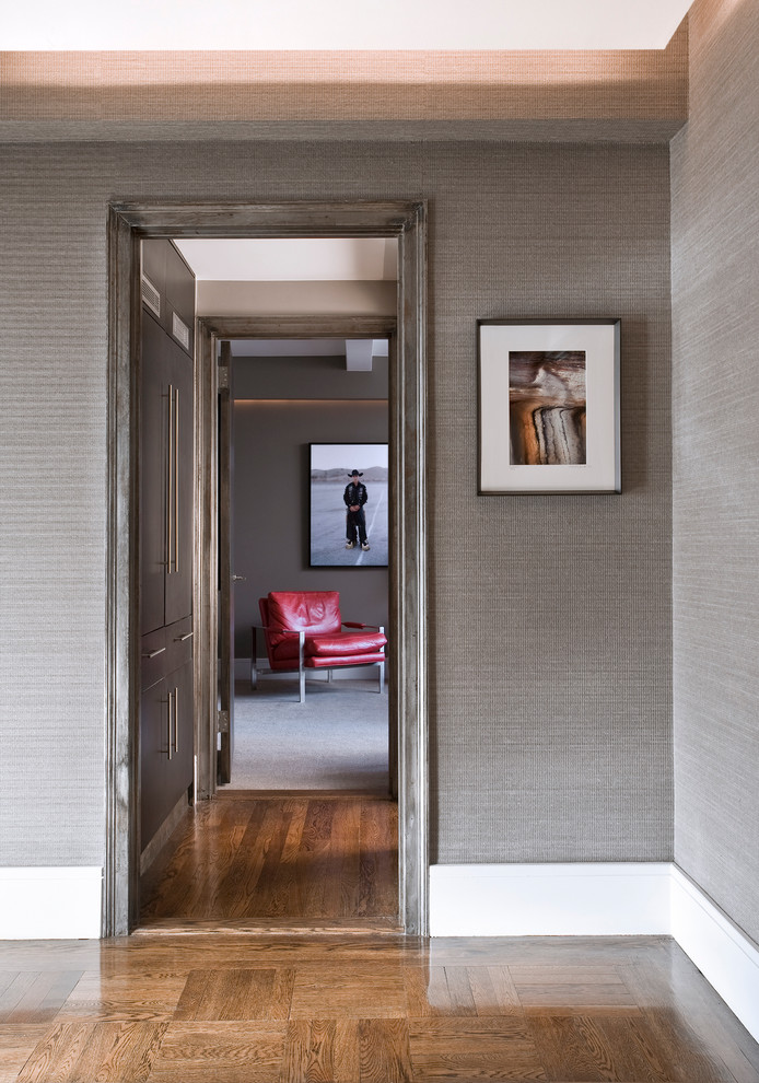 Immagine di un ingresso o corridoio minimal di medie dimensioni con pareti grigie, pavimento in legno massello medio, una porta singola e una porta in metallo