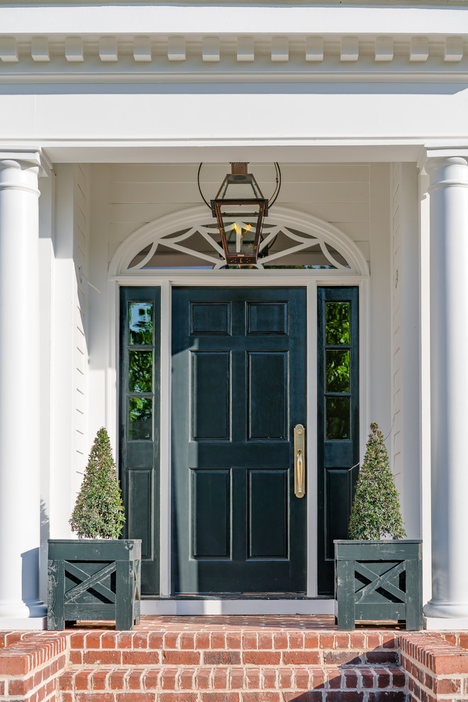Foto di una porta d'ingresso classica di medie dimensioni con pareti bianche, pavimento in mattoni, una porta singola, una porta nera e pavimento rosso