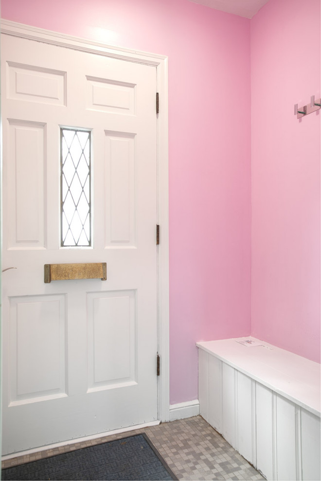 Bild på en liten 50 tals ingång och ytterdörr, med rosa väggar, vinylgolv, en enkeldörr, en vit dörr och grått golv