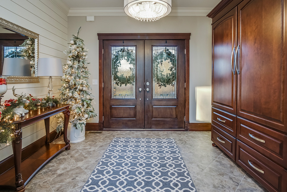 グランドラピッズにある広いトラディショナルスタイルのおしゃれな玄関ロビー (白い壁、磁器タイルの床、濃色木目調のドア、グレーの床) の写真