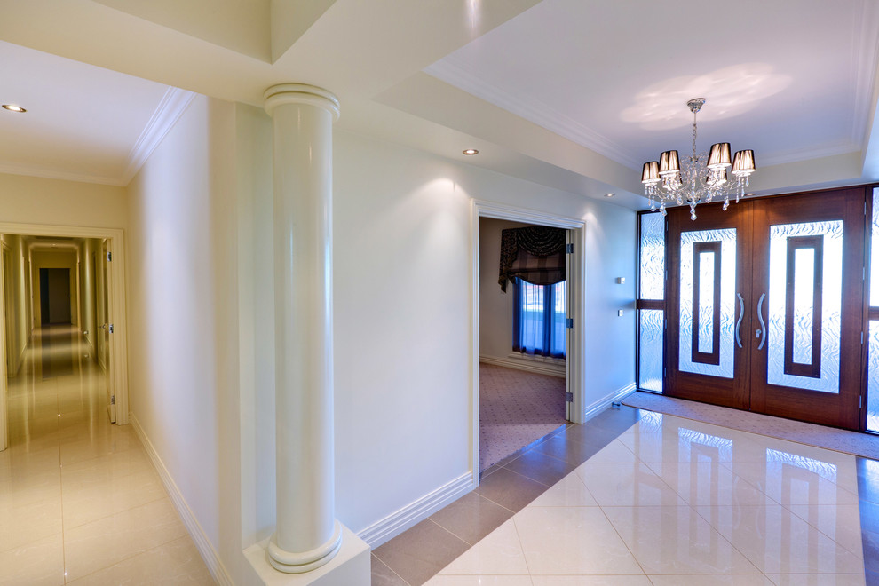 Idée de décoration pour un grand hall d'entrée design avec un mur blanc, un sol en carrelage de céramique, une porte double et une porte en bois brun.