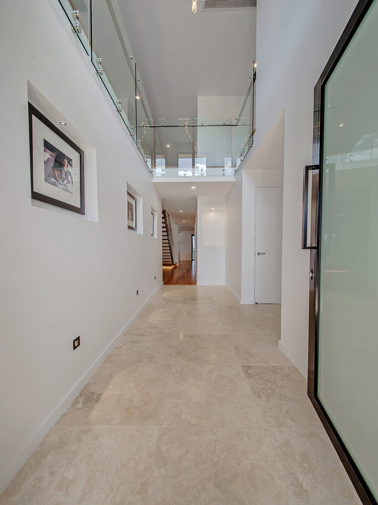 This is an example of a contemporary foyer in Brisbane with white walls, travertine flooring, a pivot front door, a glass front door and beige floors.
