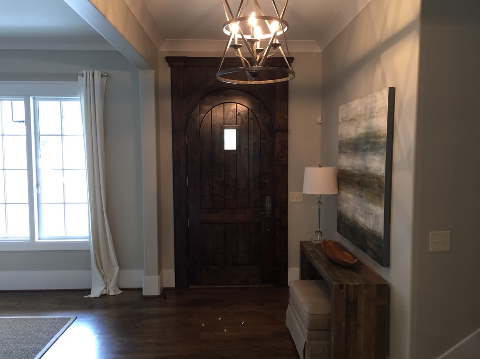 Immagine di un ingresso chic di medie dimensioni con pareti grigie, pavimento in legno massello medio, una porta singola e una porta in legno scuro
