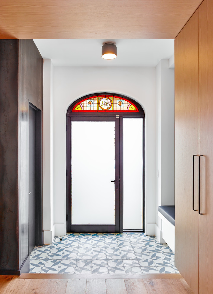 На фото: входная дверь среднего размера в современном стиле с одностворчатой входной дверью, белыми стенами, стеклянной входной дверью и разноцветным полом с