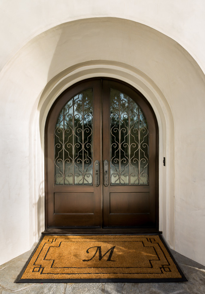 Esempio di un ingresso o corridoio mediterraneo con una porta a due ante, una porta in legno scuro e pareti beige