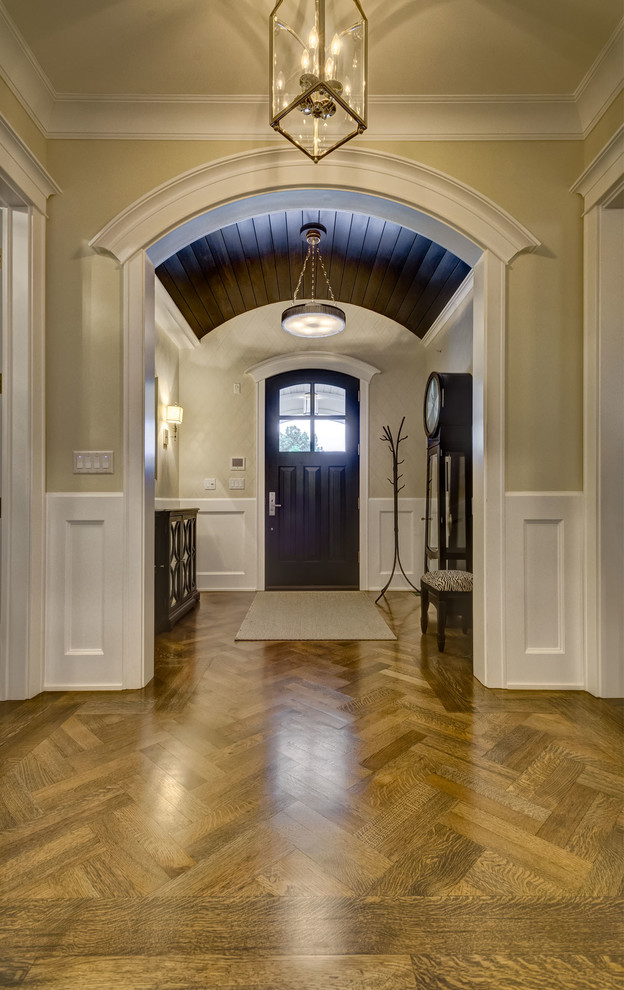 Esempio di un corridoio classico di medie dimensioni con pareti beige, pavimento in legno massello medio, una porta singola, una porta nera e pavimento marrone