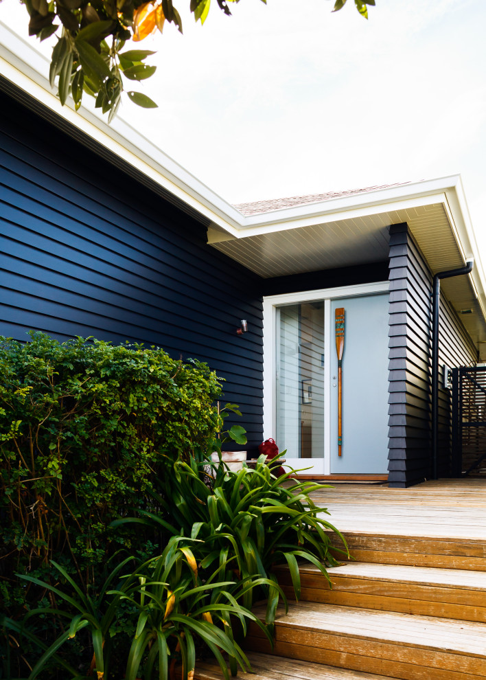 Kleine Maritime Haustür mit schwarzer Wandfarbe, gebeiztem Holzboden, Einzeltür, blauer Haustür, weißem Boden, Holzdielendecke und Holzdielenwänden in Wellington