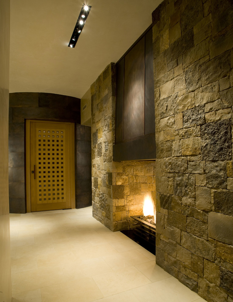 Ejemplo de distribuidor minimalista extra grande con paredes beige, suelo de piedra caliza, puerta simple, puerta de madera clara y suelo beige