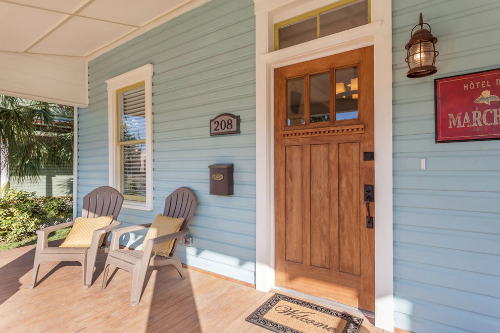 Cette image montre une grande porte d'entrée craftsman avec un mur bleu, un sol en bois brun, une porte simple et une porte en bois brun.