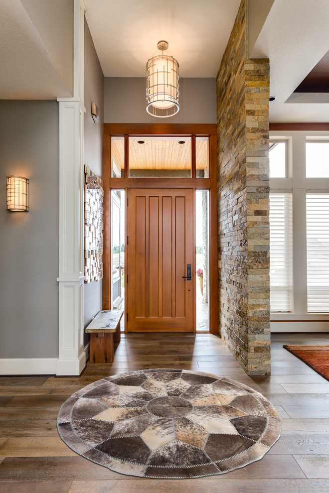 Aménagement d'un hall d'entrée classique de taille moyenne avec un mur gris, un sol en bois brun, une porte simple, une porte en bois brun et un sol marron.