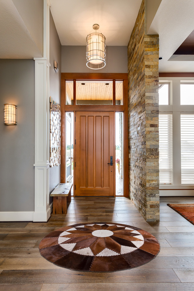Inspiration pour un hall d'entrée traditionnel de taille moyenne avec un mur gris, un sol en bois brun, une porte simple, une porte en bois brun et un sol marron.