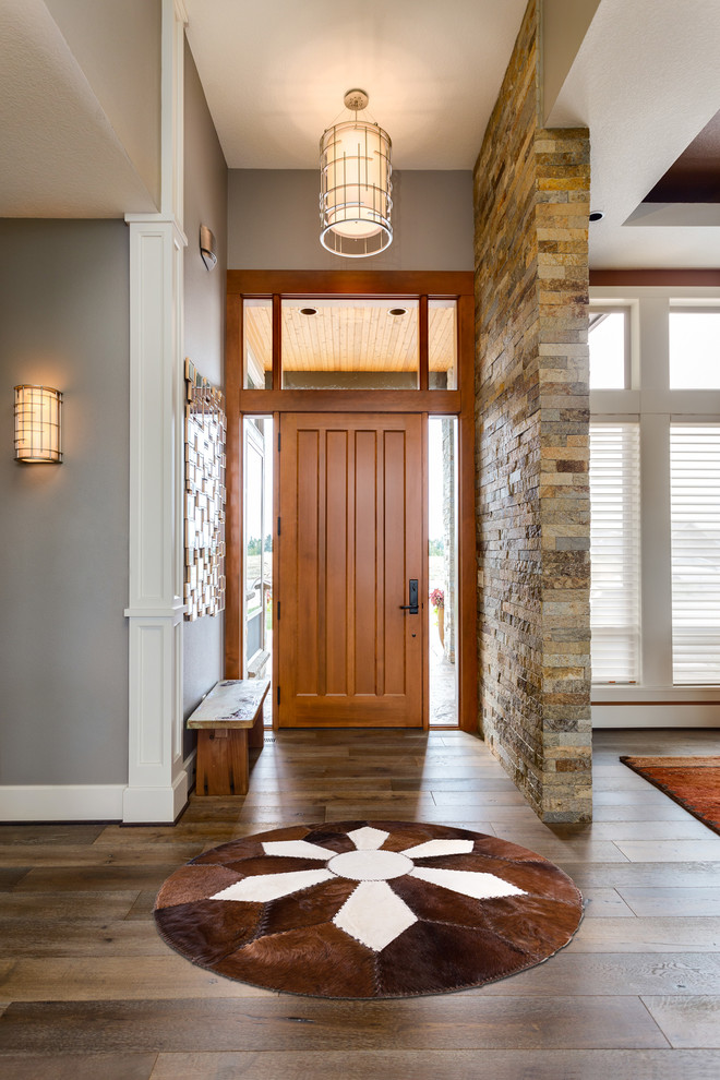 Immagine di un ingresso classico di medie dimensioni con pareti grigie, pavimento in legno massello medio, una porta singola, una porta in legno bruno e pavimento marrone