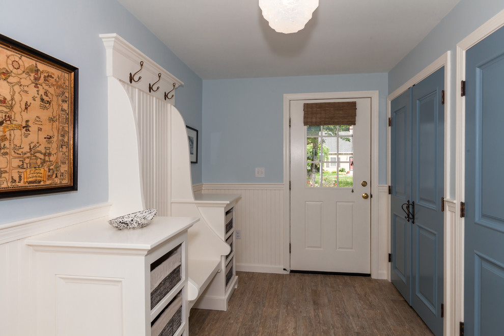 Cette image montre une entrée traditionnelle de taille moyenne avec un vestiaire, un mur bleu, un sol en carrelage de céramique, une porte simple, une porte blanche et un sol marron.