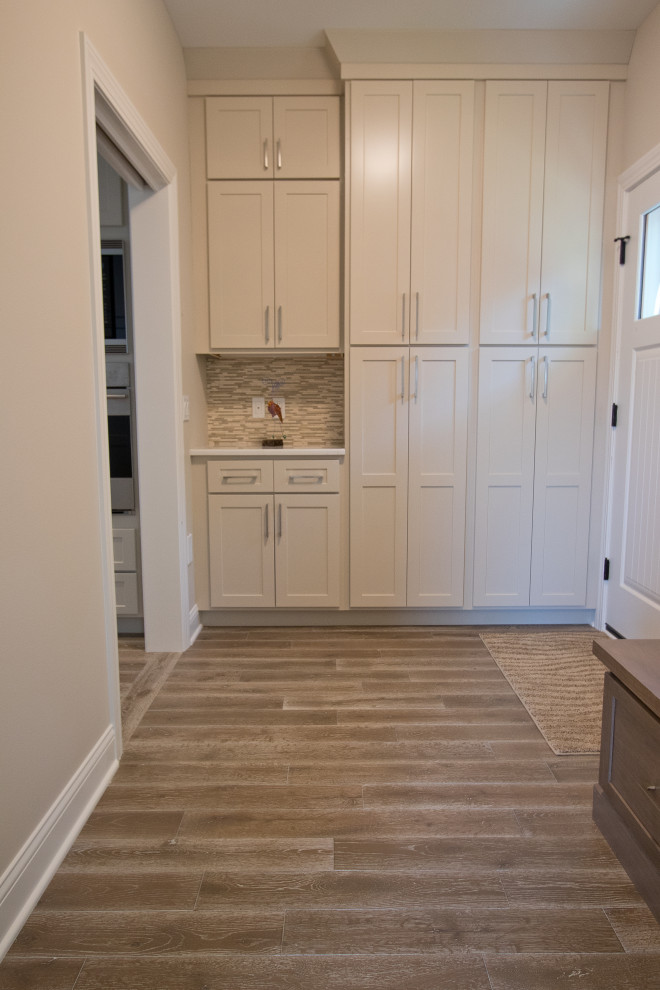 Example of a classic medium tone wood floor and brown floor mudroom design in Other with beige walls