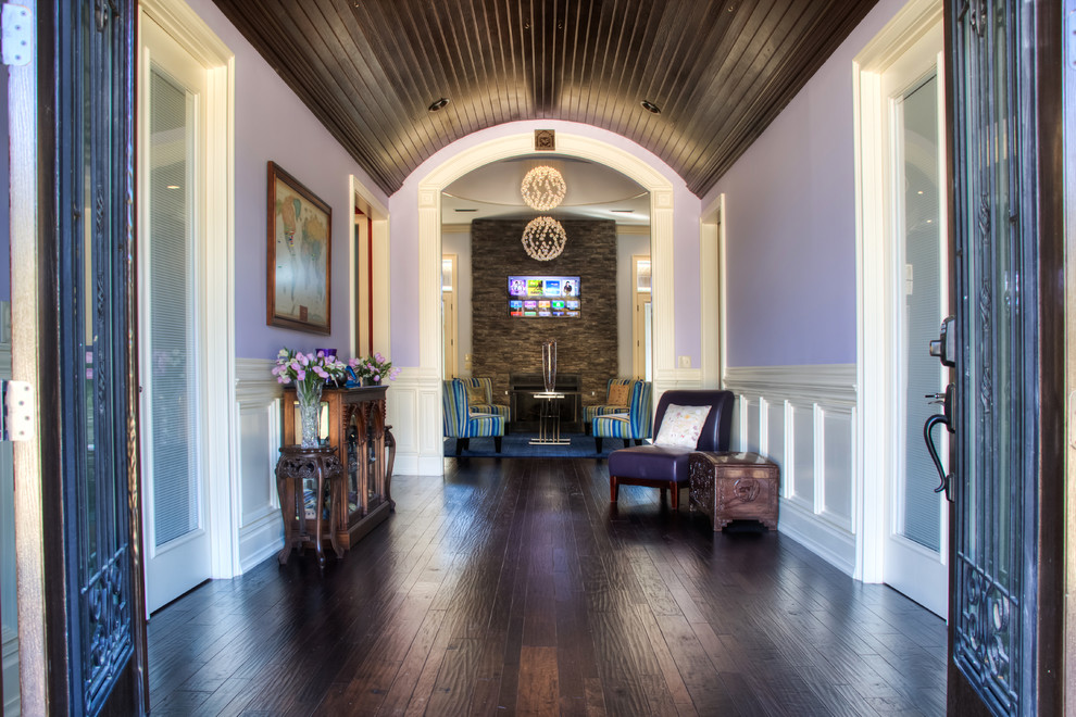 Cette photo montre un hall d'entrée tendance avec une porte double, une porte en bois foncé, un mur violet et parquet foncé.