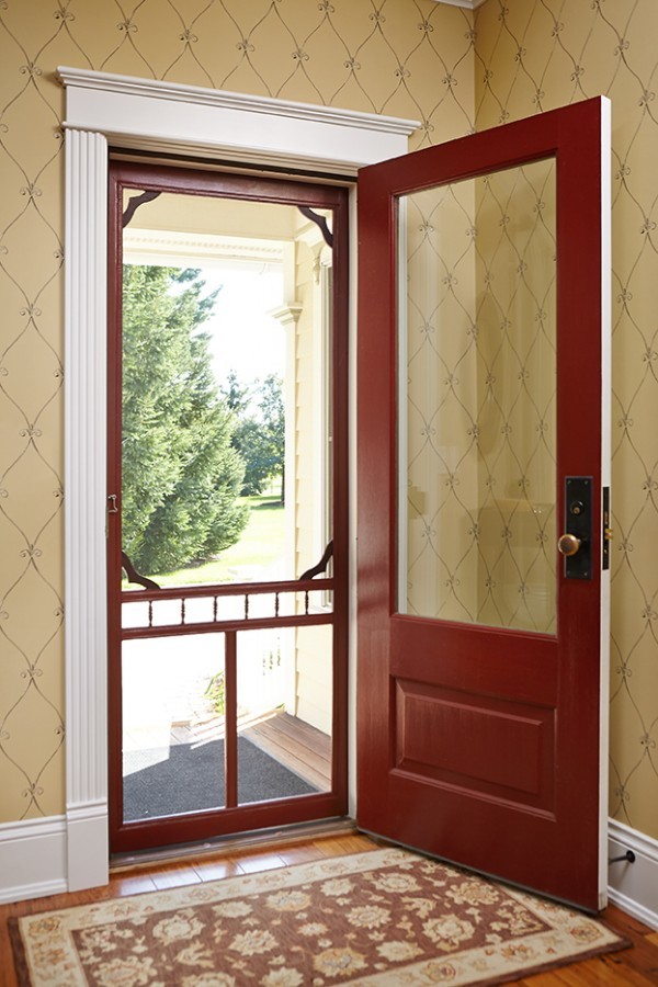 グランドラピッズにあるカントリー風のおしゃれな玄関ドア (黄色い壁、無垢フローリング、赤いドア、茶色い床、壁紙) の写真