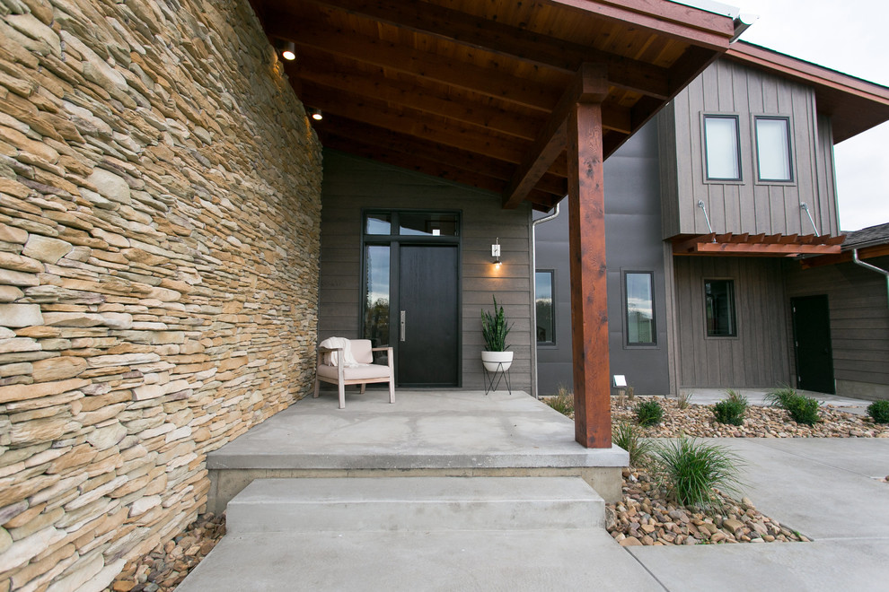 На фото: входная дверь среднего размера в стиле модернизм с разноцветными стенами, бетонным полом, одностворчатой входной дверью, черной входной дверью и серым полом