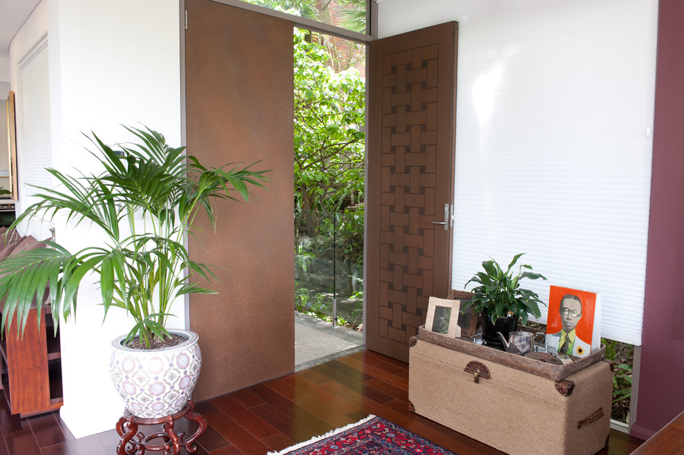 Diseño de puerta principal de tamaño medio con paredes rosas, suelo de madera oscura, puerta doble y puerta marrón