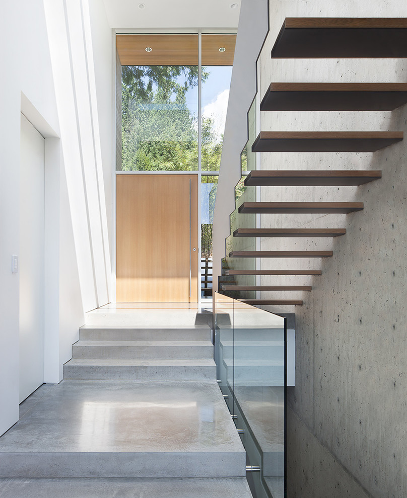 Exemple d'une porte d'entrée moderne avec un mur blanc, sol en béton ciré, une porte simple et une porte en bois clair.