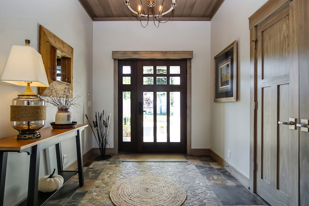 Example of a mid-sized arts and crafts slate floor and multicolored floor entryway design in Grand Rapids with white walls and a dark wood front door