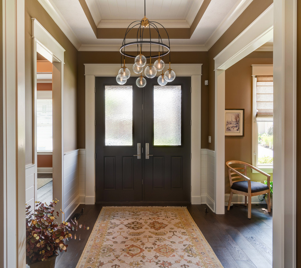 Idee per un ingresso american style di medie dimensioni con pareti arancioni, parquet scuro, una porta a due ante, una porta in legno scuro e pavimento marrone