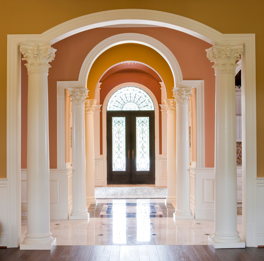 Cette image montre un grand hall d'entrée traditionnel avec un sol en marbre, un mur multicolore, une porte double, une porte noire et un sol marron.