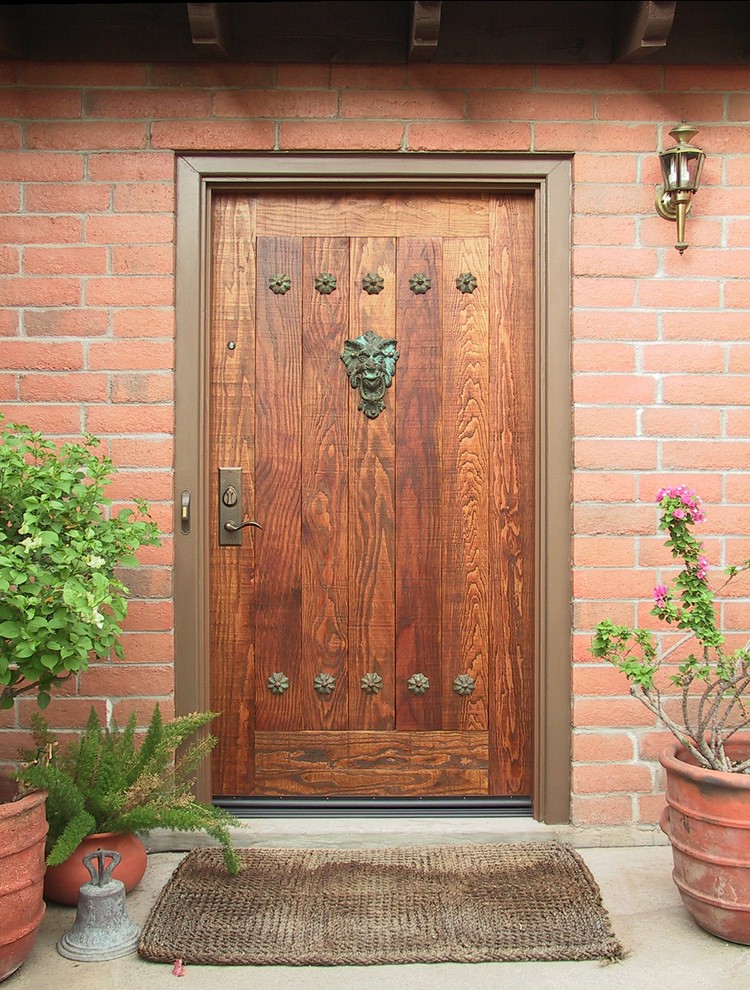 Modelo de puerta principal rural de tamaño medio con parades naranjas, suelo de cemento, puerta simple y puerta de madera en tonos medios