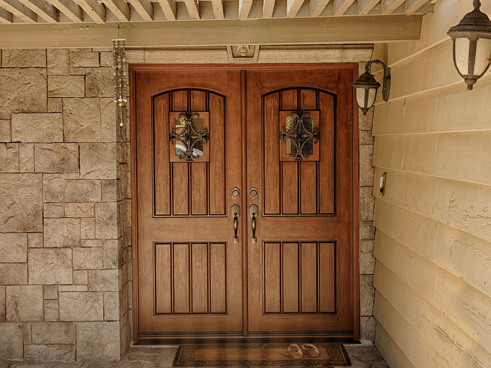 На фото: огромная входная дверь в стиле рустика с коричневыми стенами, двустворчатой входной дверью и входной дверью из дерева среднего тона