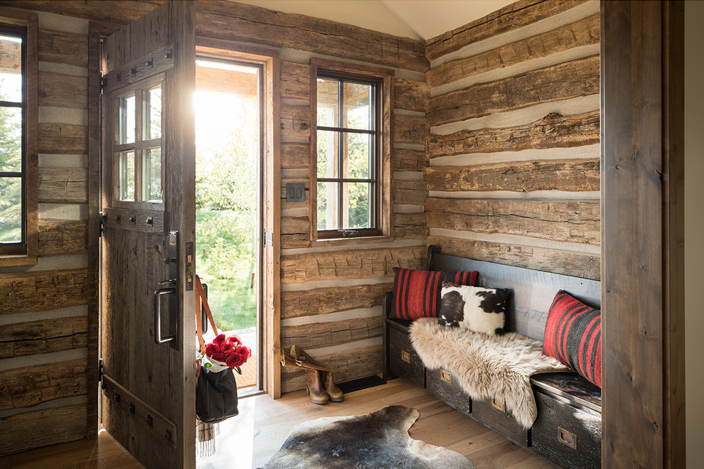 Rustik inredning av en entré, med en enkeldörr, ljust trägolv och beiget golv