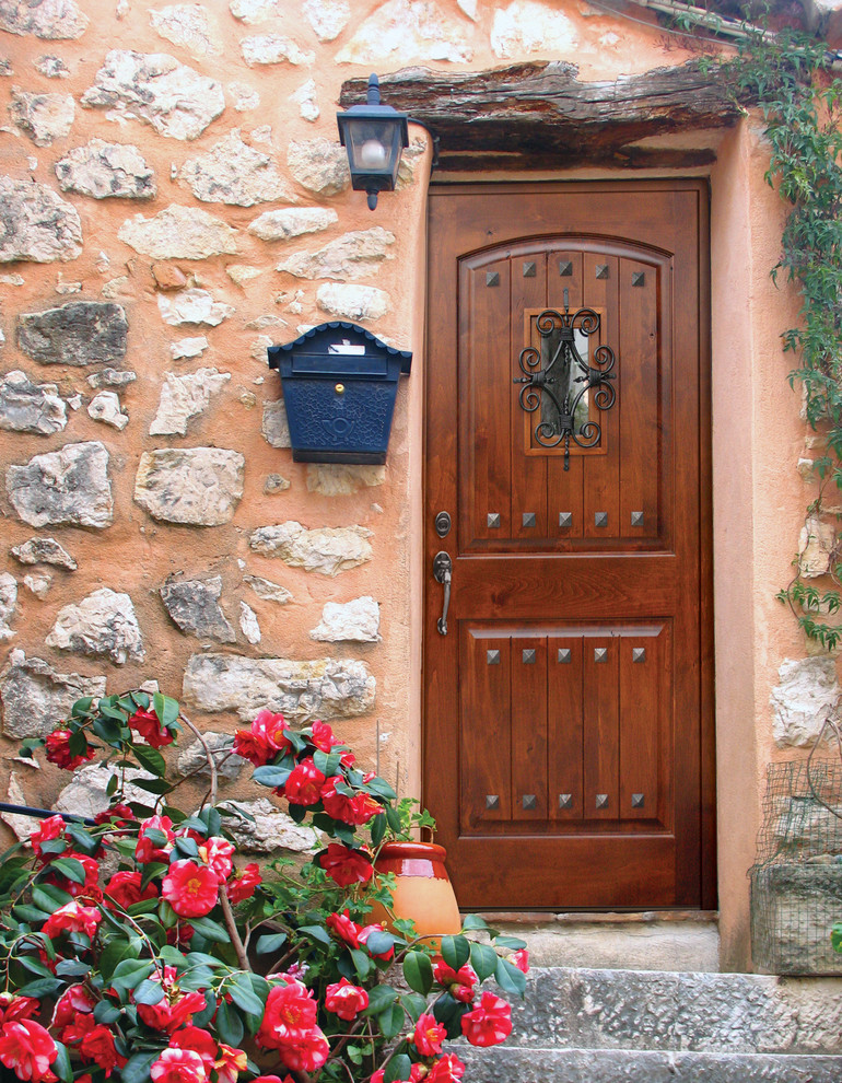 Пример оригинального дизайна: входная дверь среднего размера в средиземноморском стиле с оранжевыми стенами, одностворчатой входной дверью и входной дверью из темного дерева
