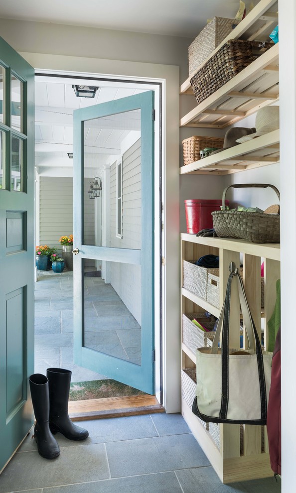 Lantlig inredning av ett litet kapprum, med vita väggar, skiffergolv, en enkeldörr, en blå dörr och blått golv