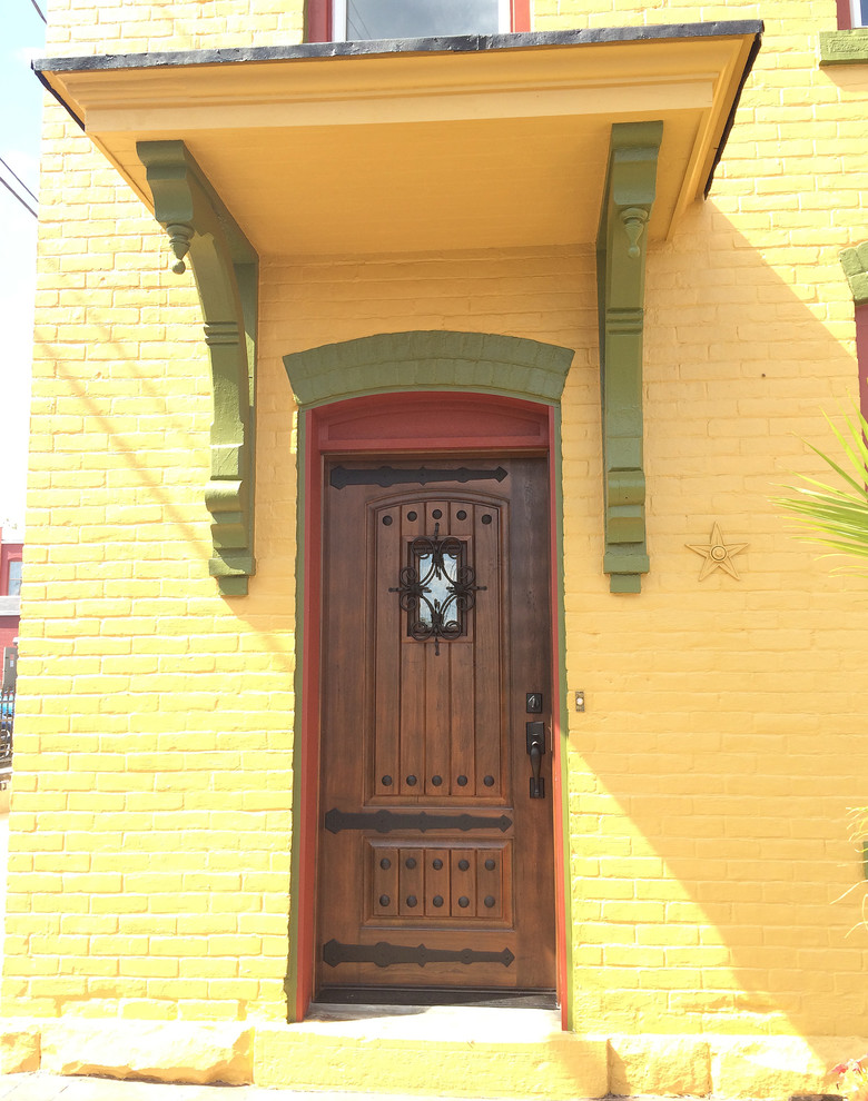 Réalisation d'une porte d'entrée sud-ouest américain avec un mur jaune, une porte simple et une porte en bois foncé.