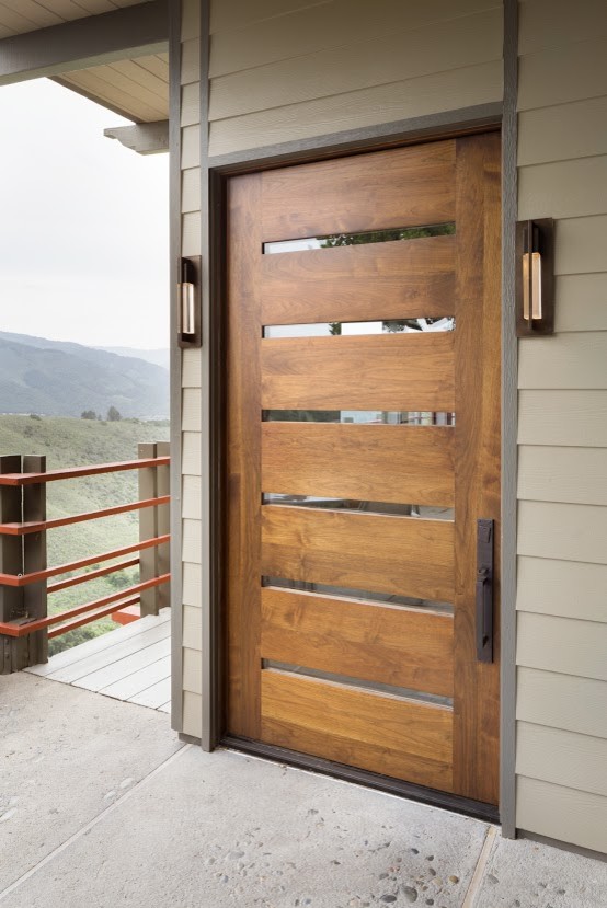 Aménagement d'une grande porte d'entrée montagne avec un mur marron, sol en béton ciré, une porte pivot et une porte en bois brun.