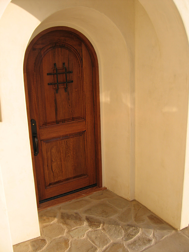 サンタバーバラにある高級な中くらいな地中海スタイルのおしゃれな玄関ドア (黄色い壁、ライムストーンの床、木目調のドア、ベージュの床) の写真