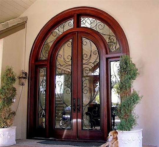 Große Mediterrane Haustür mit Doppeltür, dunkler Holzhaustür, beiger Wandfarbe und Kalkstein in Los Angeles