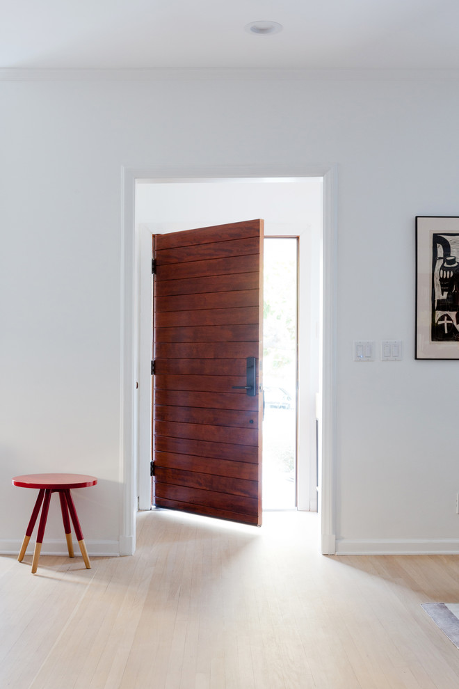 Ejemplo de distribuidor actual de tamaño medio con paredes blancas, suelo de madera clara y puerta de madera en tonos medios