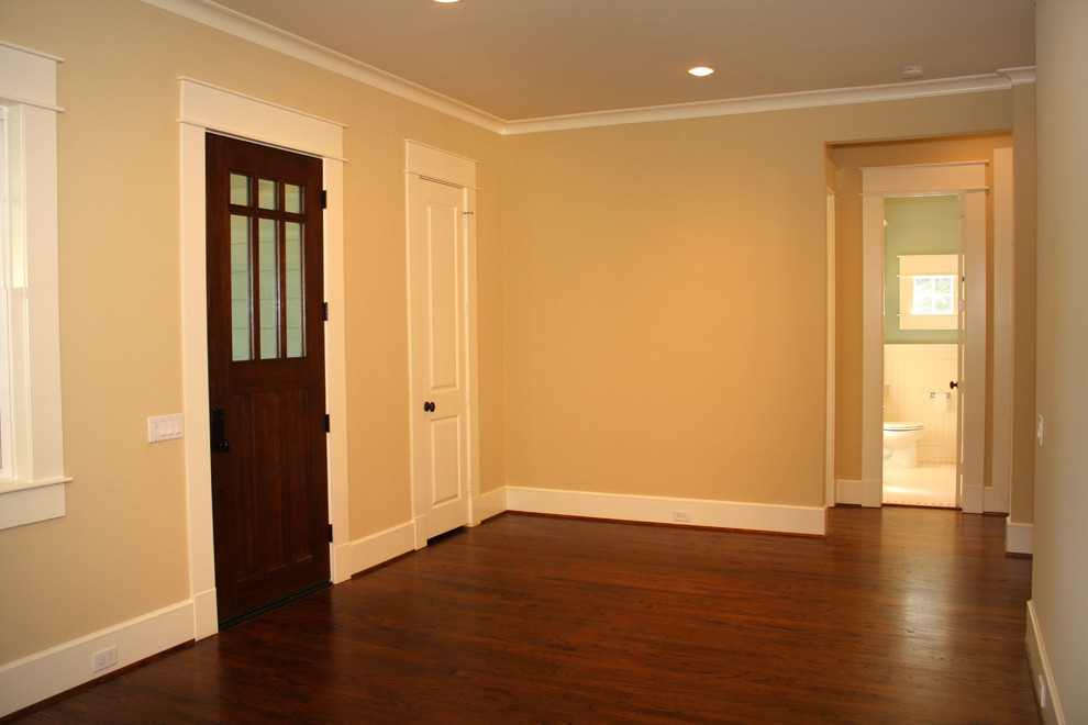 Mittelgroßes Klassisches Foyer mit gelber Wandfarbe, braunem Holzboden, Einzeltür und brauner Haustür in Houston