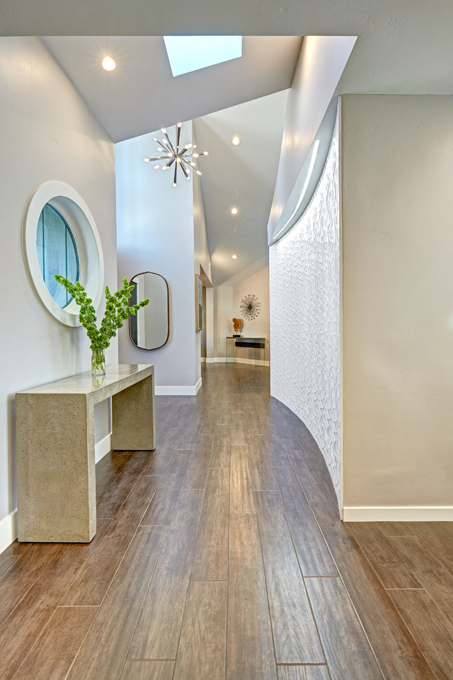Inspiration pour une entrée design de taille moyenne avec un sol en bois brun, un couloir et un mur gris.