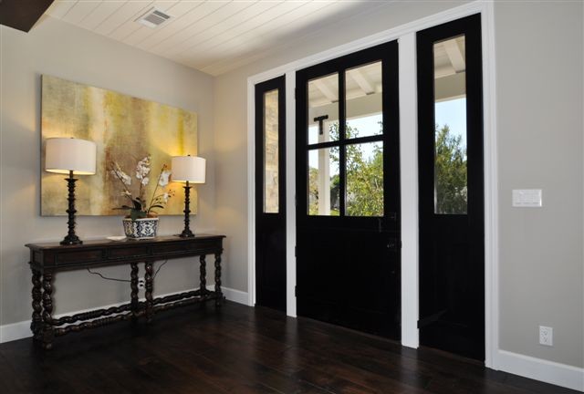 Modelo de puerta principal tradicional renovada de tamaño medio con paredes grises, suelo de madera oscura y puerta de madera oscura