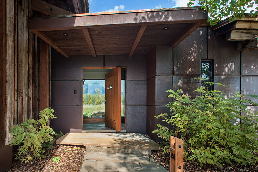 Ispirazione per una porta d'ingresso design con pareti con effetto metallico, pavimento in ardesia, una porta a pivot e una porta in legno bruno